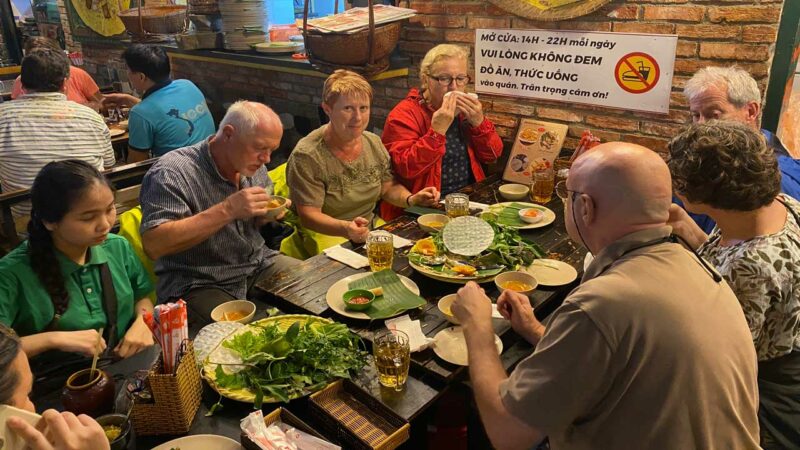 サイゴンのグルメツアーで美味しいベトナム料理を楽しむ観光客